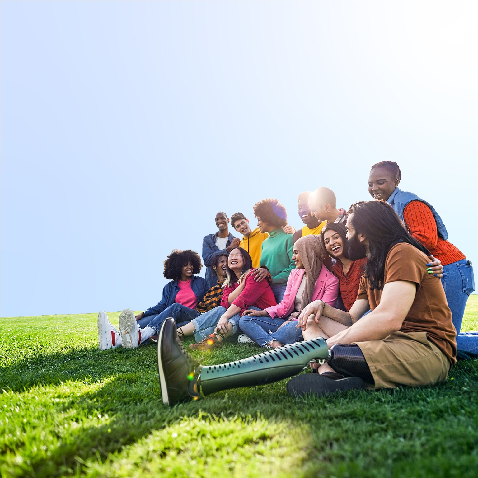 Diverse multiethnic people enjoying themselves outdoors sitting on the grass in a city park
