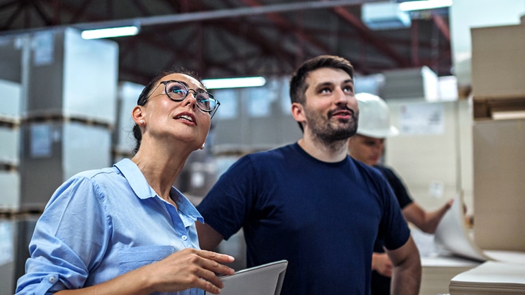 Image of a warehouse supervisor walking and talking with a senior manager while inspecting a warehouse.