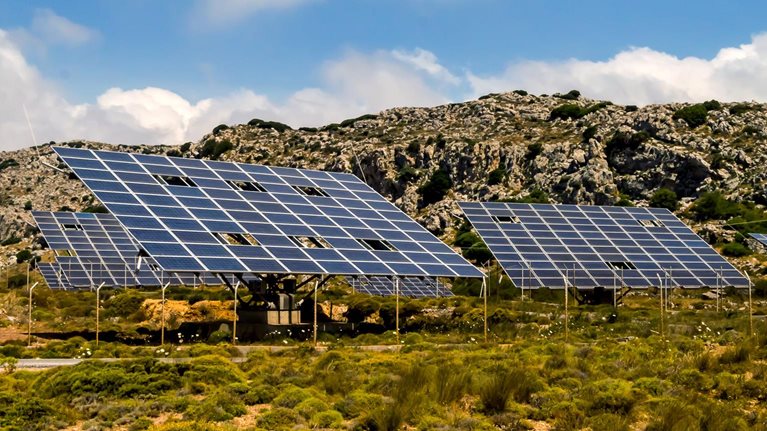 A solar farm on the foothills of a rocky terrain. 