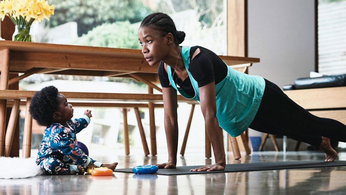 Person doing push ups, being watched by infant