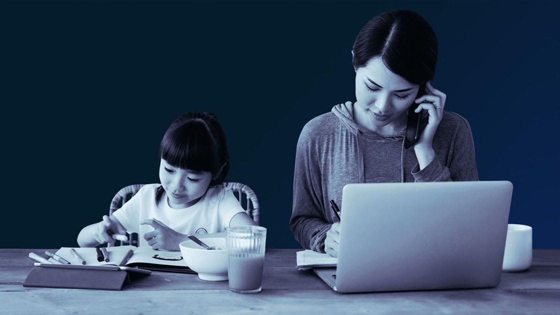 person talking on the phone and looking at her laptop, next to a child.