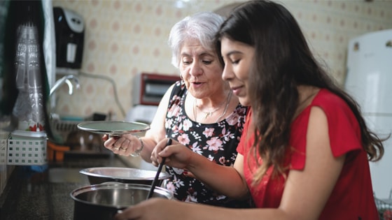 Two people looking at a pot in a kitchen