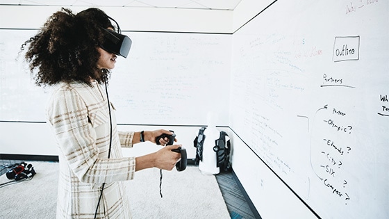 A person wearing virtual reality goggles and holding controls