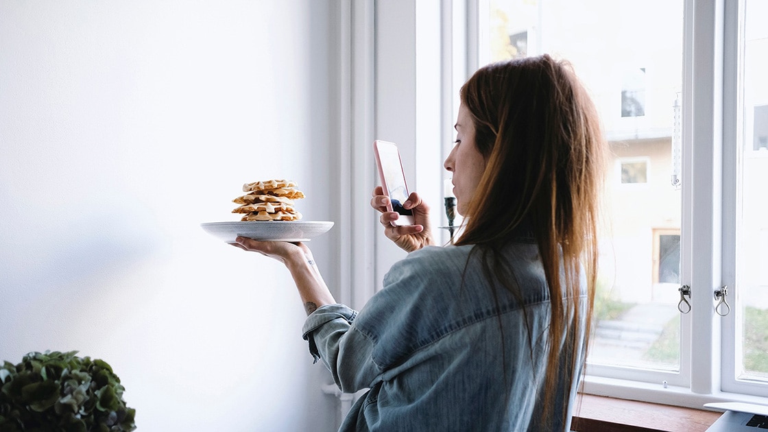 Image of a woman taking a photo of her food at home