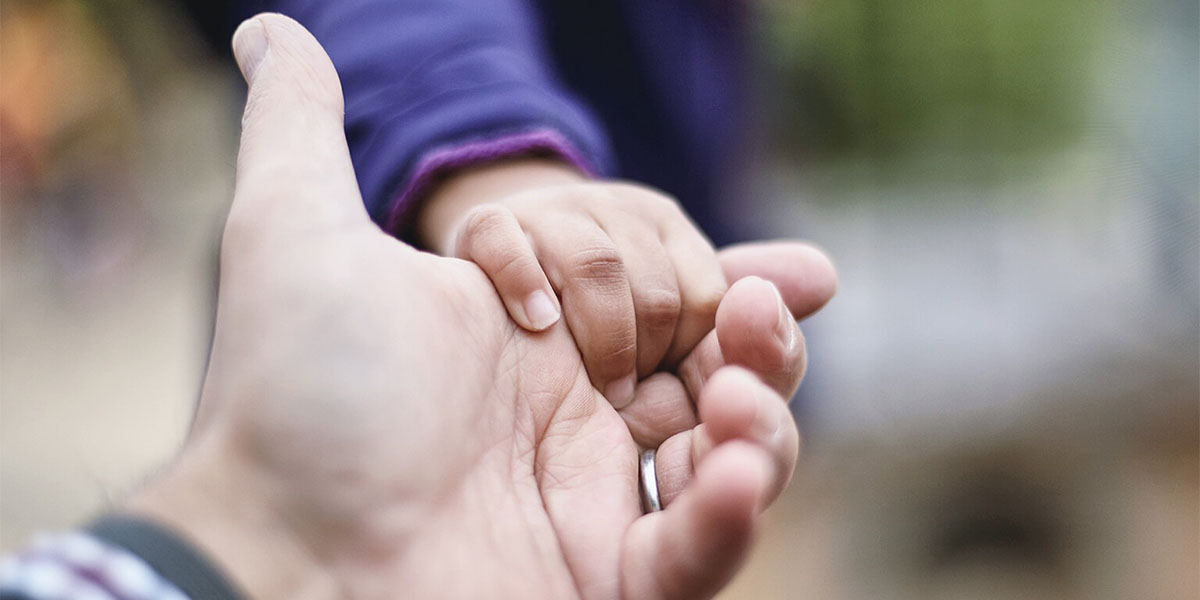 A photo of a man holding a child's hand