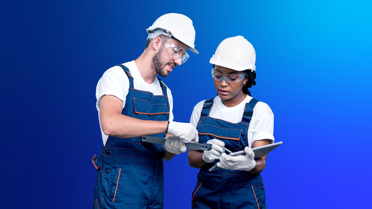 Image of two workers in hard hats and overalls in front of a blue backdrop