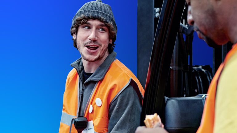 Image of two workers wearing orange vests and conversing