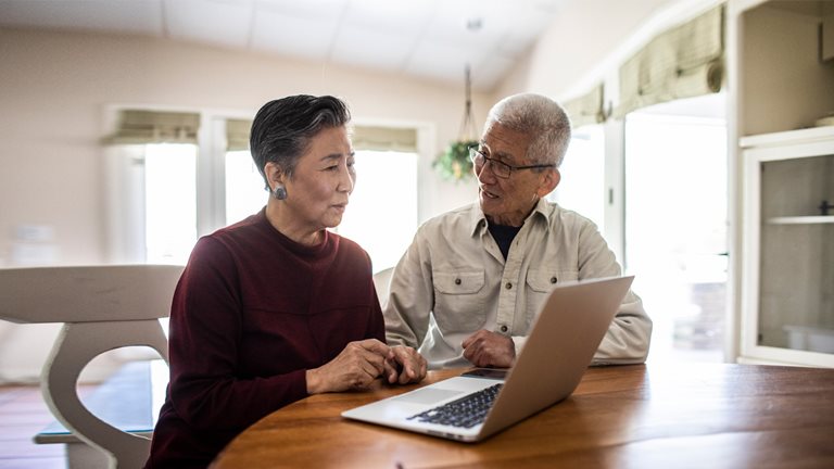 Image of elderly couple talking in front of open laptop