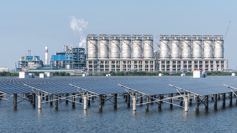 Solar panels in water with power plant in background