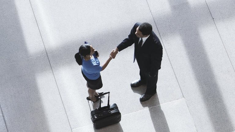 Overhead view of two colleagues shaking hands in an office