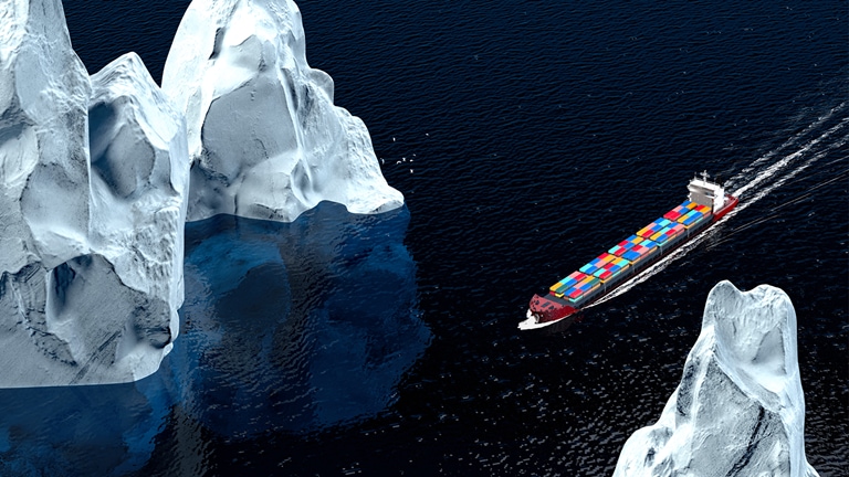 Photo of a container ship passing by large icebergs