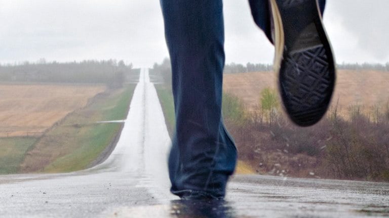 Image of a person running in the rain on an empty countryside road