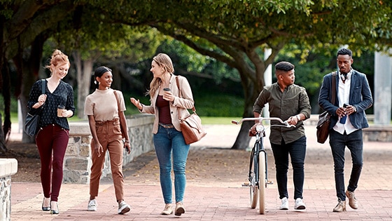 Image of five people walking down a pedestrian plaza while talking