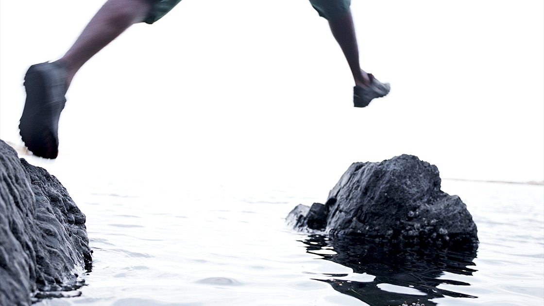 Image of a person hopping onto a rock in water