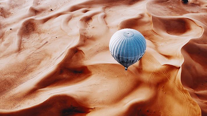 Photo of a hot air balloon flying over a desert