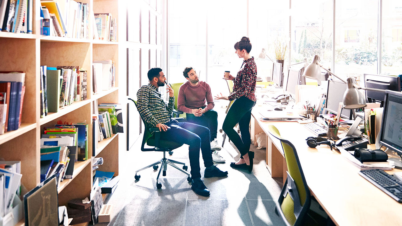 Image of three colleagues talking in an office setting