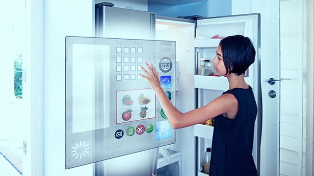 Image of a woman looking at a digital screen in front of an open refrigerator
