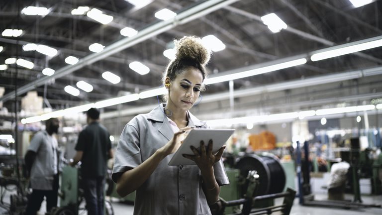 Female worker in a manufacturing plant looking at a mobile tablet