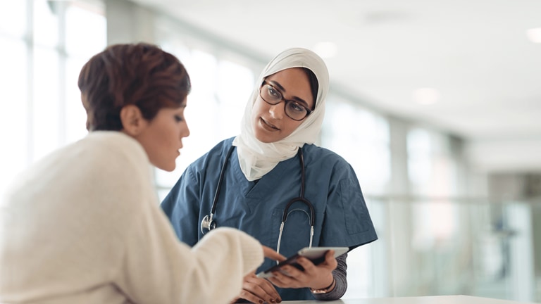 Image of Saudi Arabian nurse with tablet helping patient