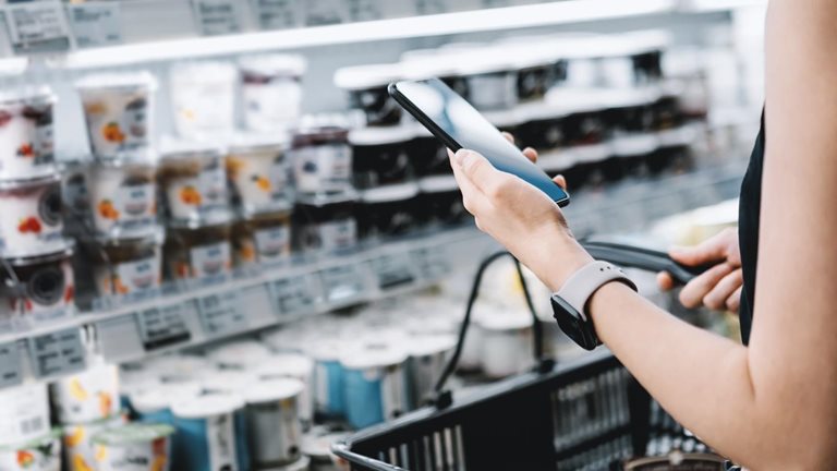 Image of a person holding a cell phone in a grocery store