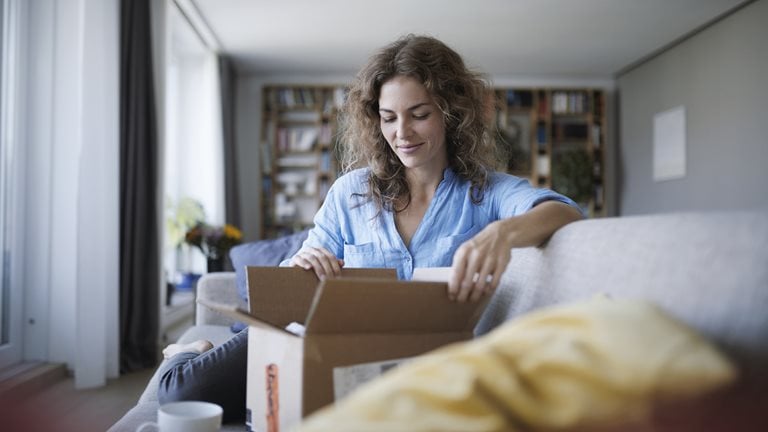 Image of a woman opening a box on a couch