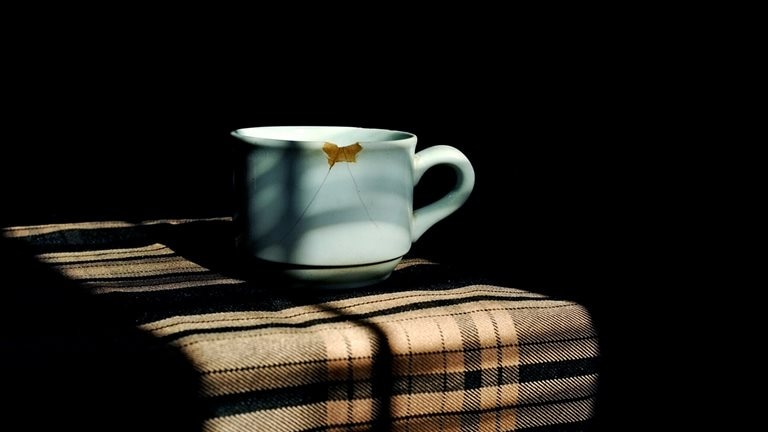 Close-Up Of Broken Coffee Cup Against Black Background