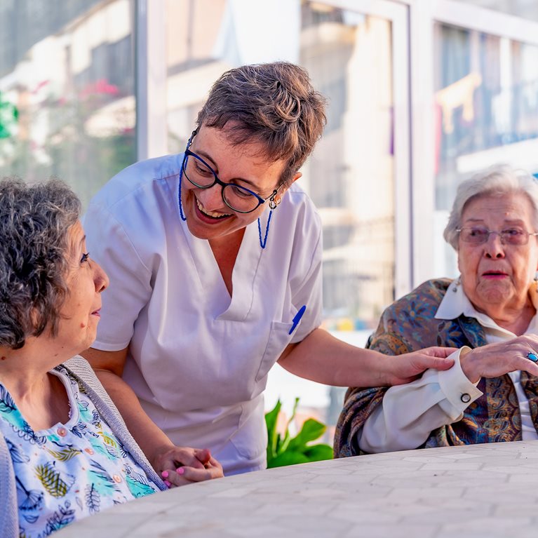Nurse visiting seniors sitting in the garden of a geriatric