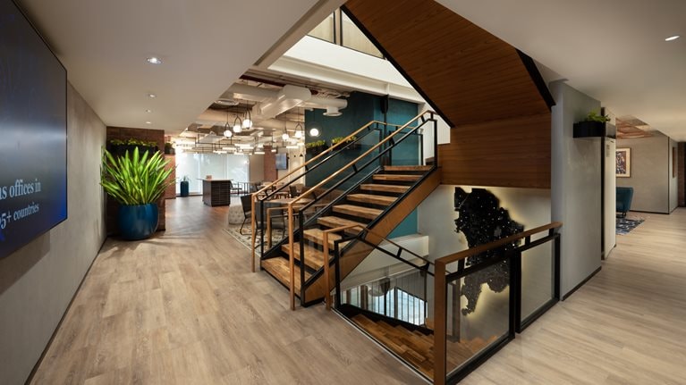 Stylish stairwell with wooden steps and glass railing in the hallway of McKinsey's Mumbai office