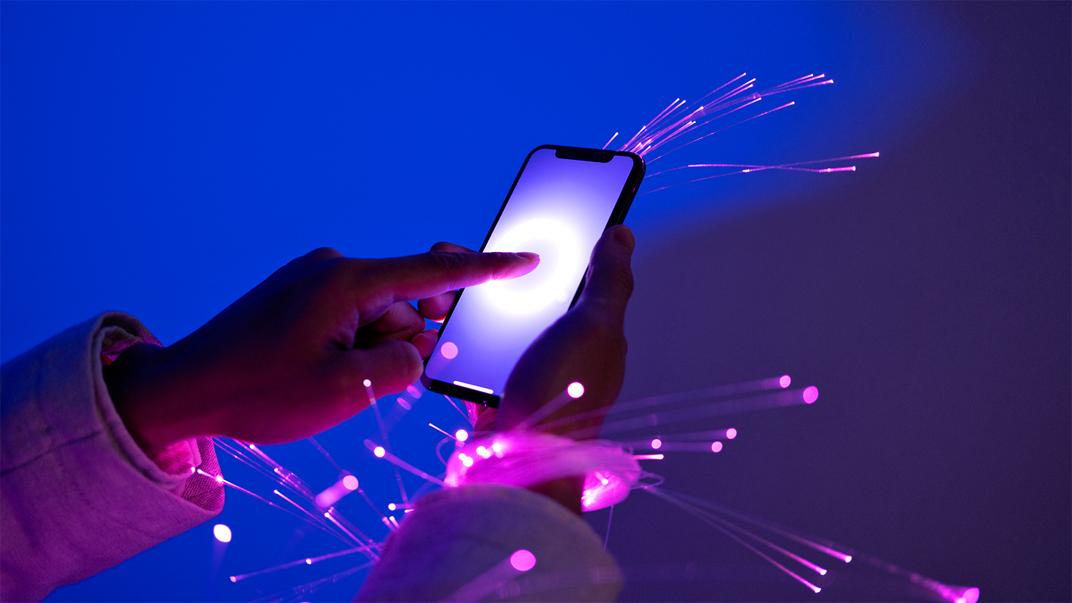 Person holding a smartphone with sparks flying to illustrate fiber optic connection