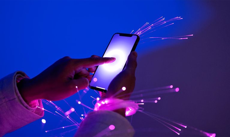 Person holding a smartphone with sparks flying to illustrate fiber optic connection