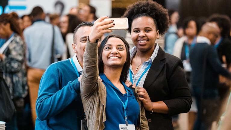 Woman taking a selfie with colleagues at an event