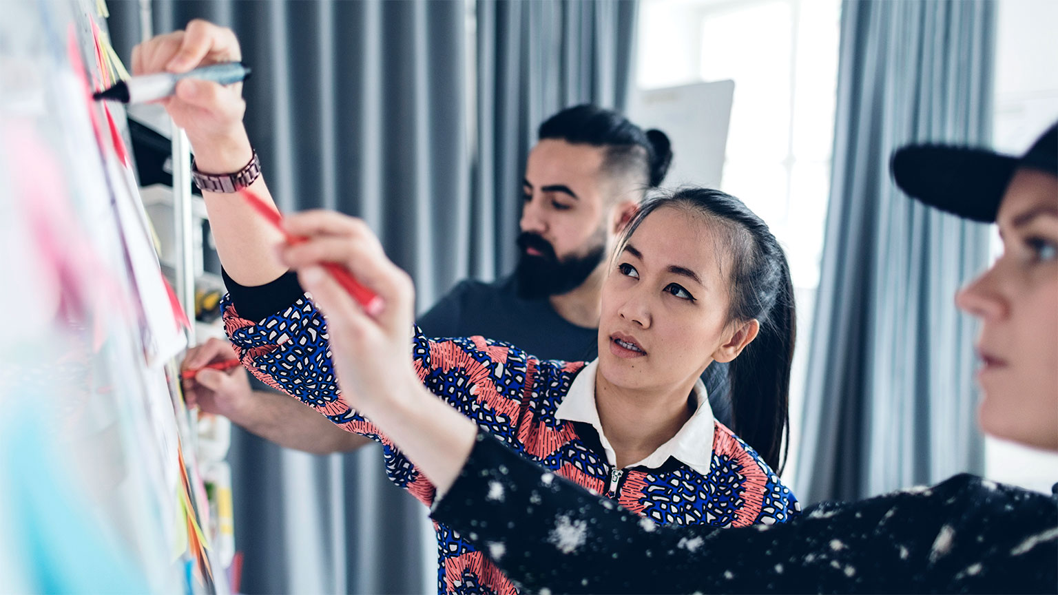 people writing on whiteboard in board room
