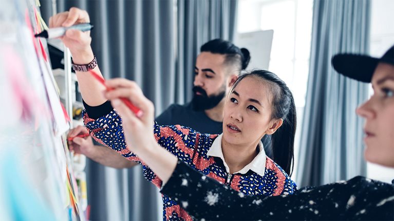 people writing on whiteboard in board room