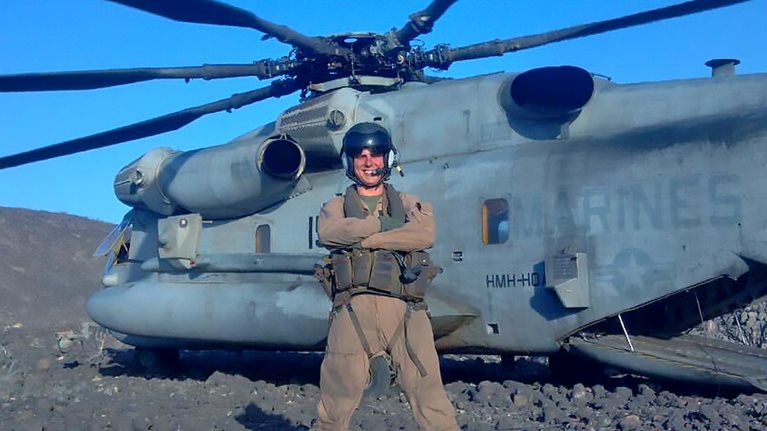 McKinsey Associate Partner Tyler Freeman standing next to a military helicopter