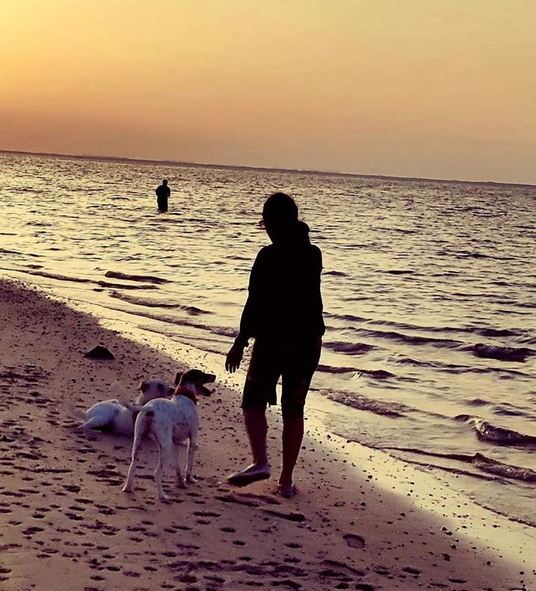 Padma and her dog at the beach during sunset