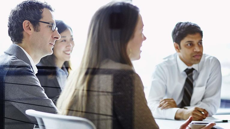 Business meeting with four people gathered around conference table