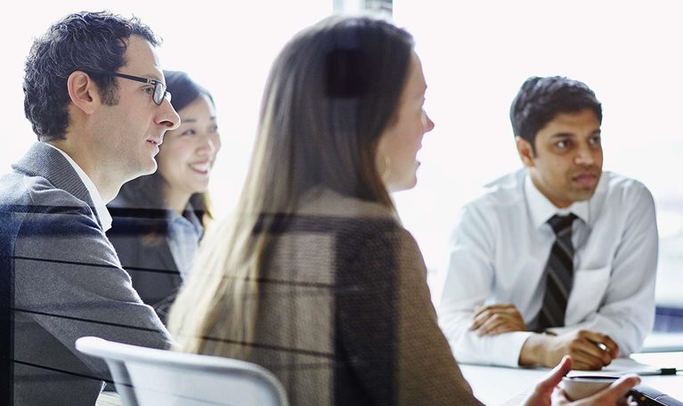 Business meeting with four people gathered around conference table