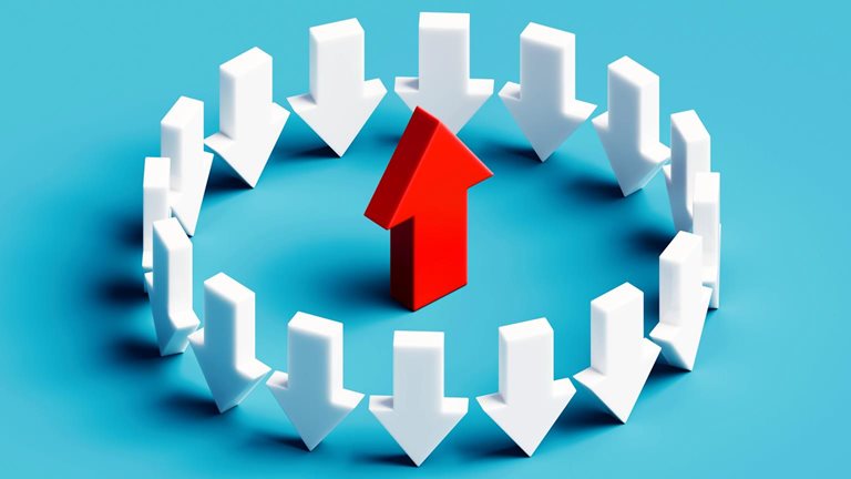 A striking conceptual illustration showing a circle of white arrows all pointing downward, contrasted by a bold red arrow in the center pointing upward. 