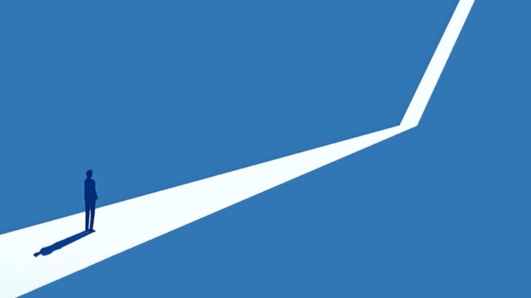 Silhouette of a person standing at the start of a branching path against a blue background.