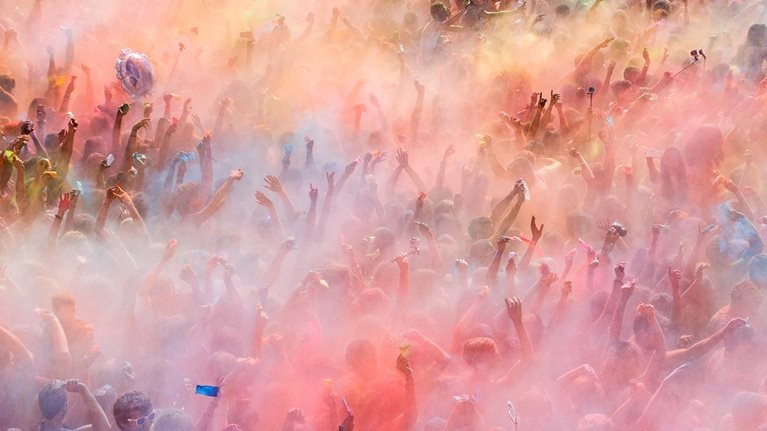 People throwing colored powders and dancing during the celebration of the Holi festival