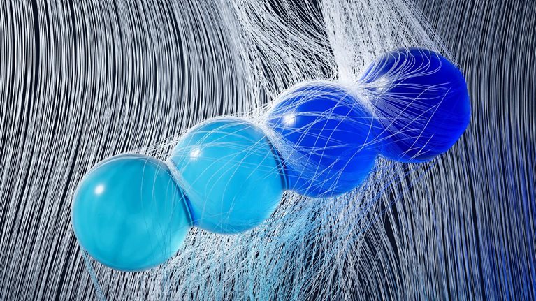 Four glass spheres in varying shades of blue are suspended in midair, tangled in a cascade of fine white threads.
