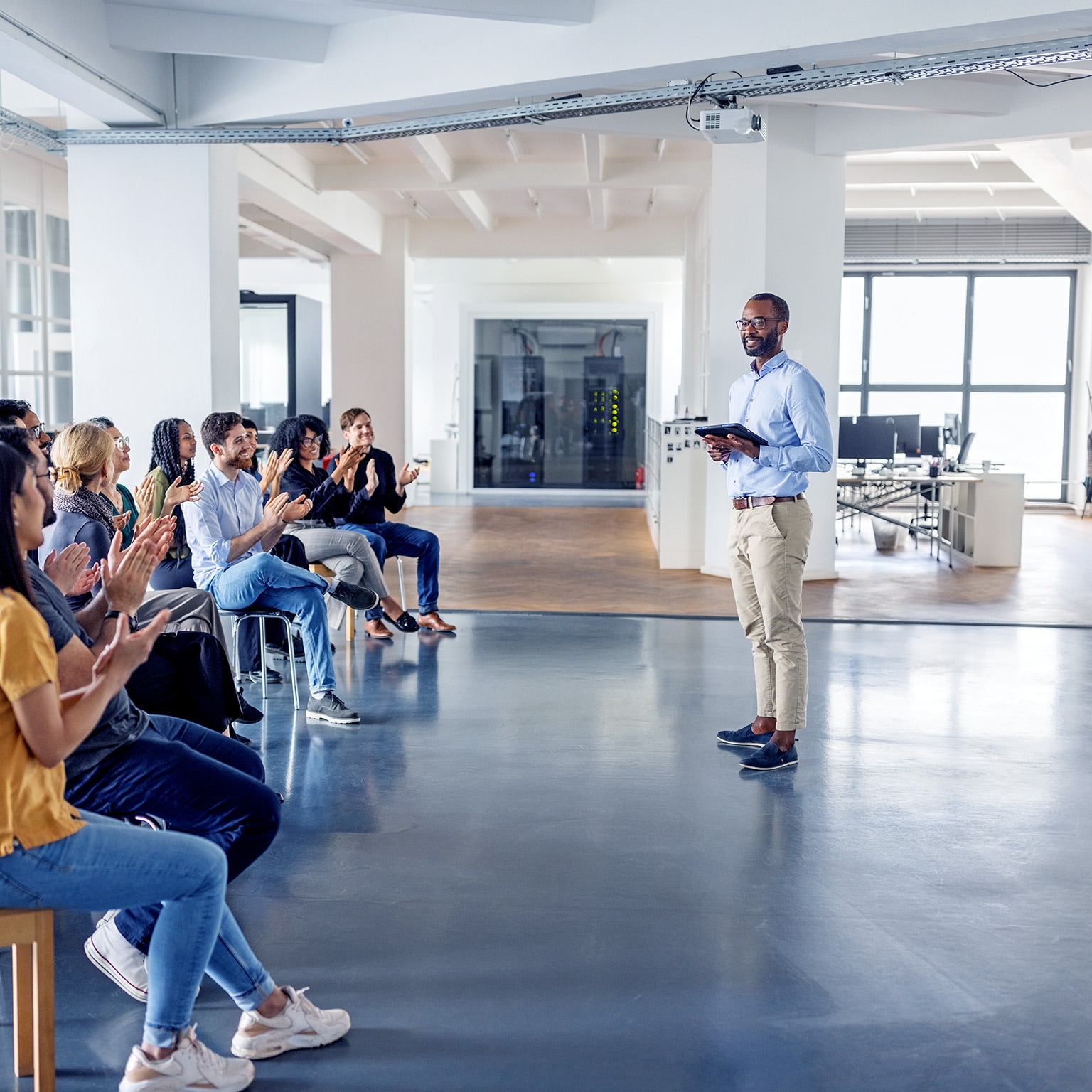An image of a business team clapping and celebrating at a team-building session in a modern office.