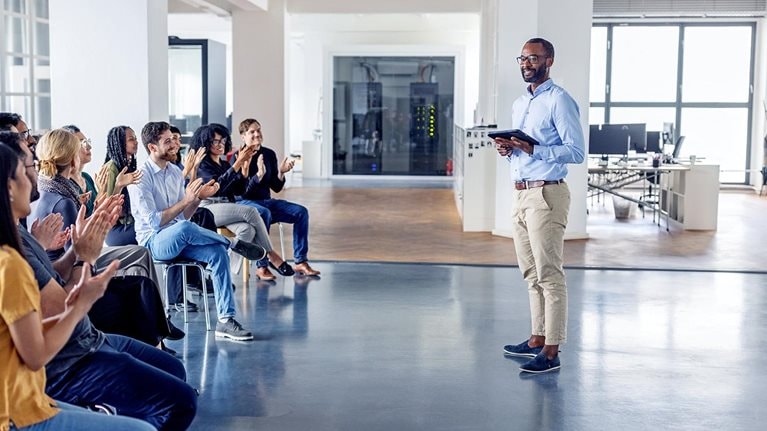 An image of a business team clapping and celebrating at a team-building session in a modern office.