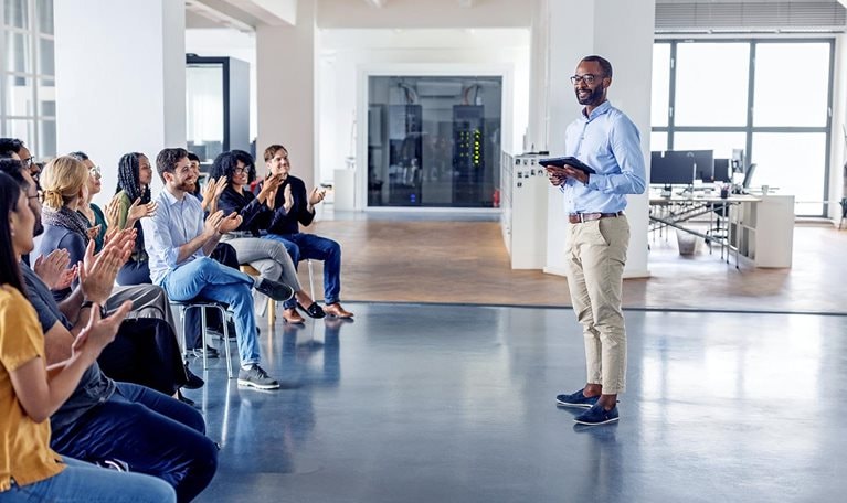 An image of a business team clapping and celebrating at a team-building session in a modern office.