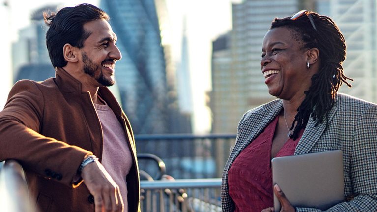 Two colleagues having work discussion at rooftop garden in a high-rise office building