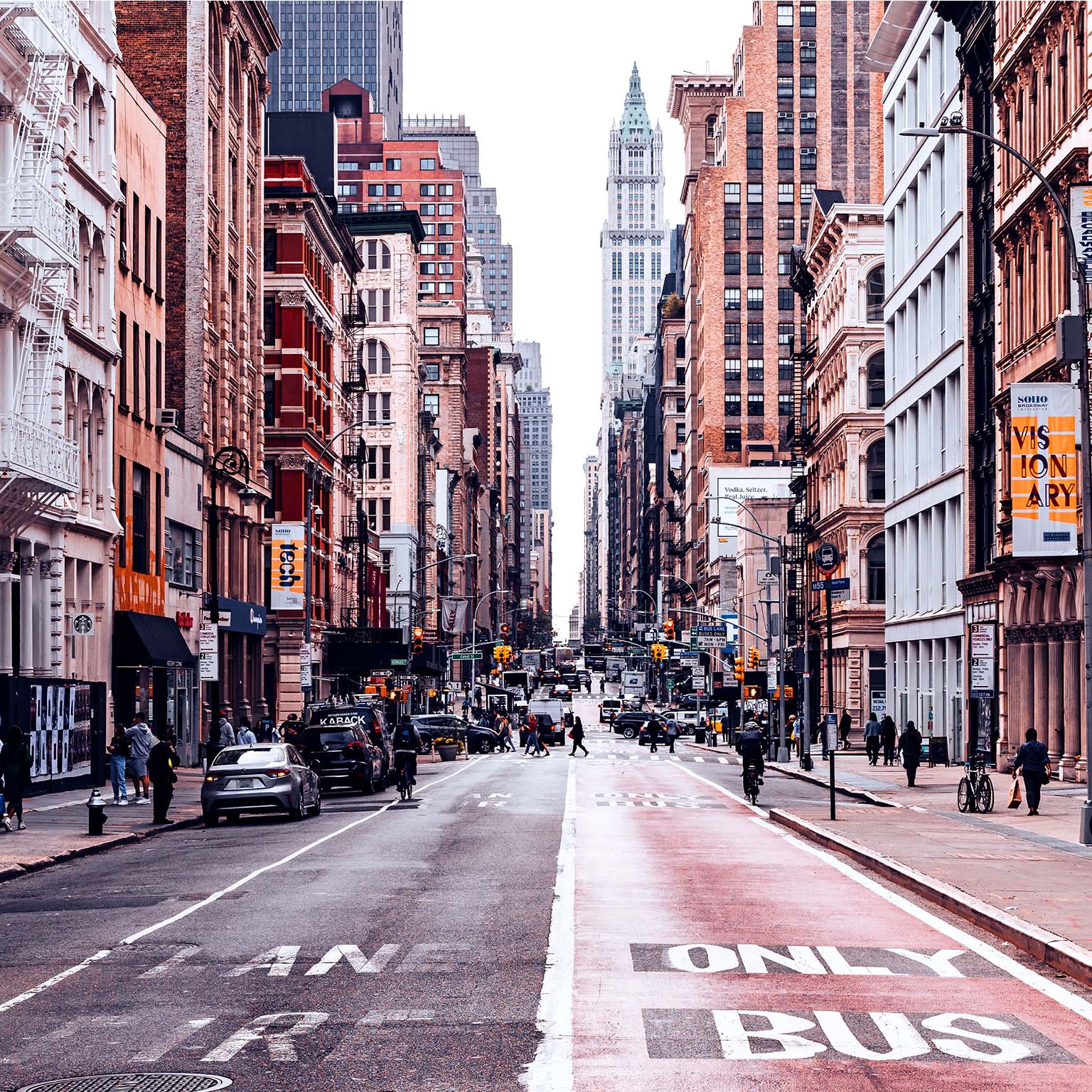 A bustling New York City street lined with historic buildings, shops, and pedestrians.