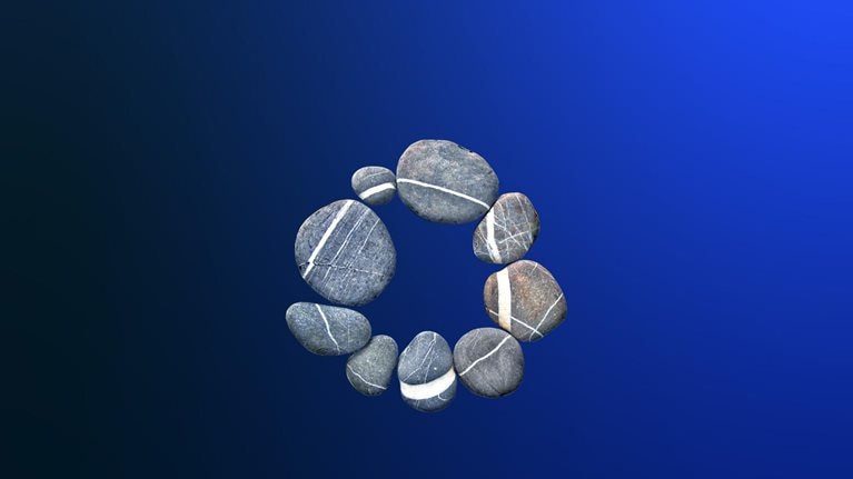 A circle made up of nine smooth, gray river stones sits on a dark blue gradient. Each stone contains a white vein, forming a secondary circle when they are arranged in this way.