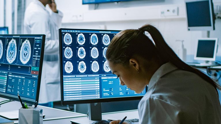 Team of Professional Scientists Work in the Brain Research Laboratory. Neurologists / Neuroscientists Surrounded by Monitors Showing CT, MRI Scans Having Discussions and Working on Personal Computers. - stock photo