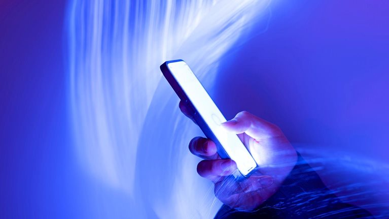Close-up of using mobile phone on holographic background