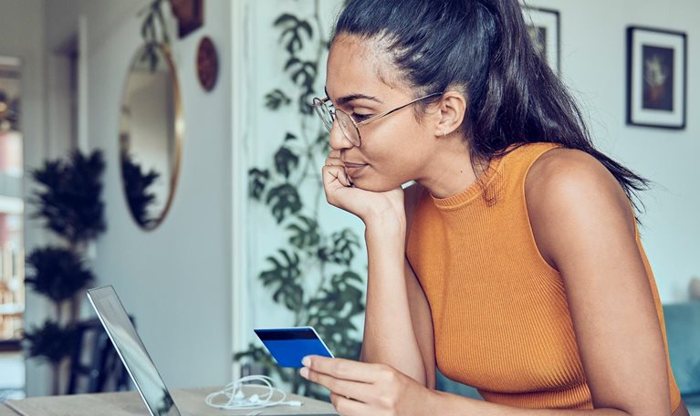 photo woman in apartment online shopping on laptop with credit card in hand